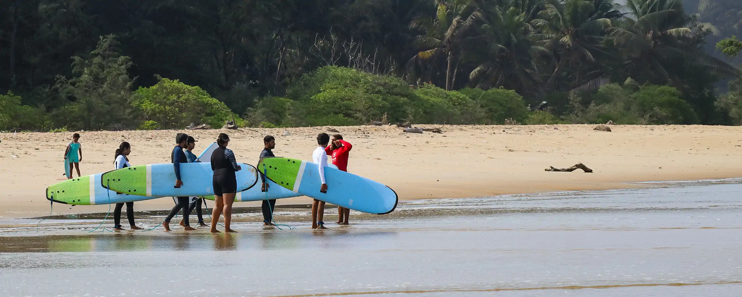 Group of surfers carrying boards into the water during a surf session