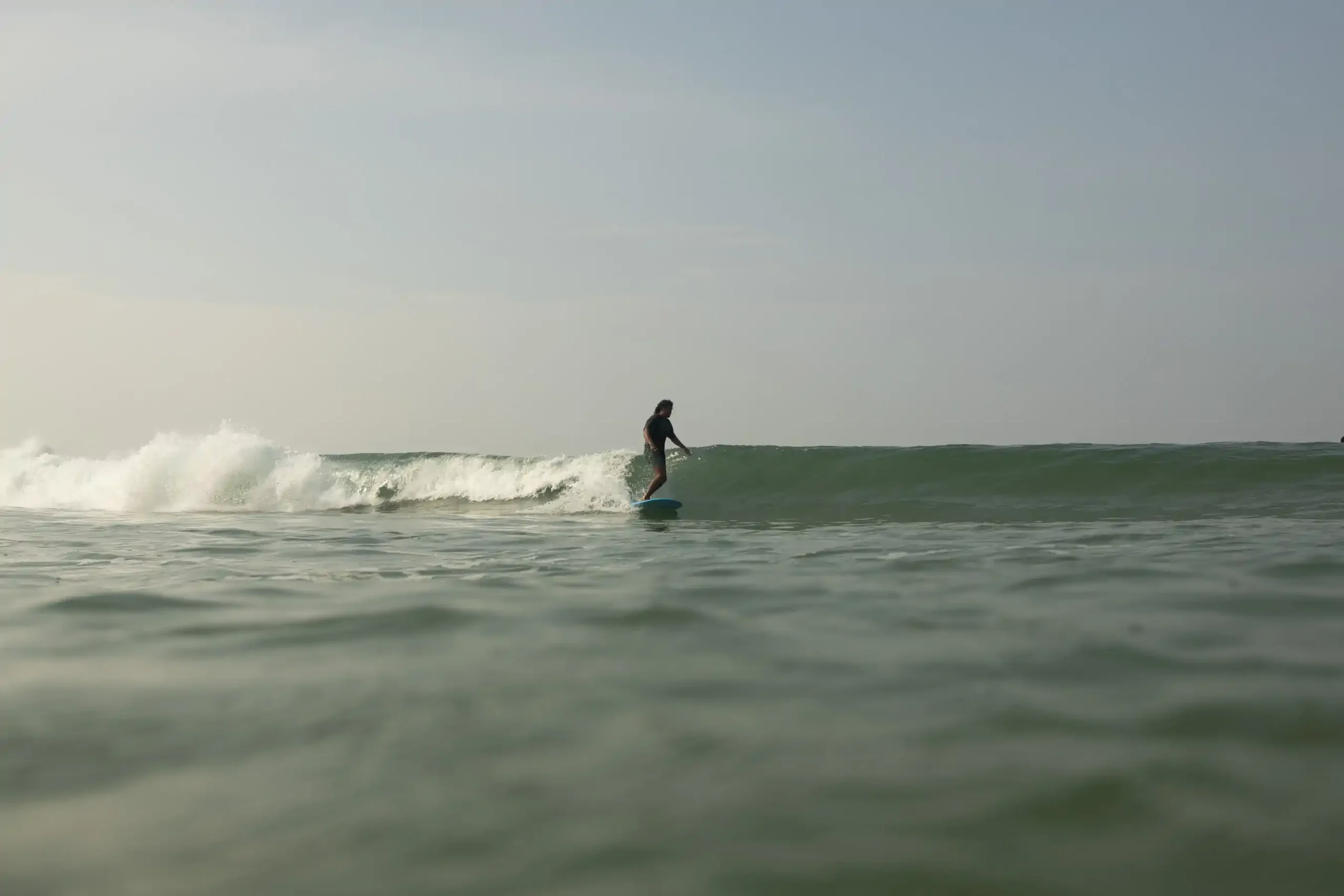 Surfer walking through shallow water carrying a surfboard
