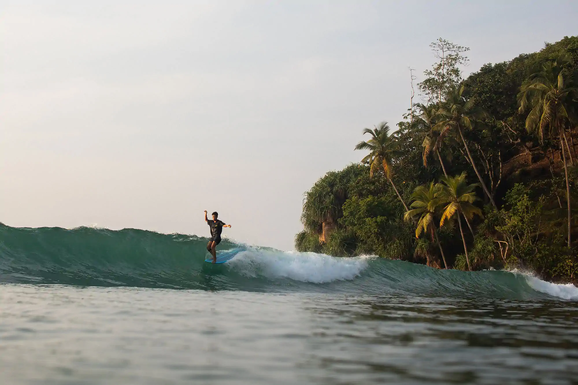 Surfer walking through shallow water carrying a surfboard